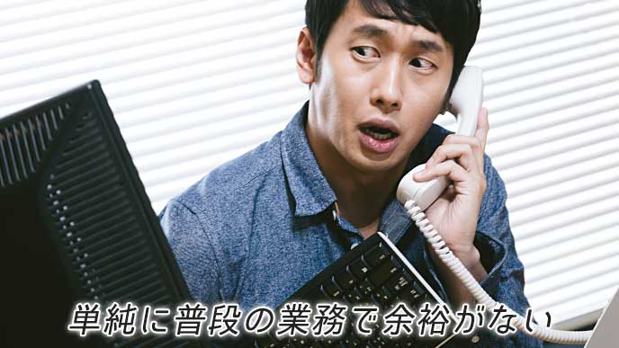 キーボードを持ちながら電話応対をする会社員