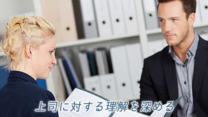 書類をまとめたファイルを開き上司に内容を説明する会社員