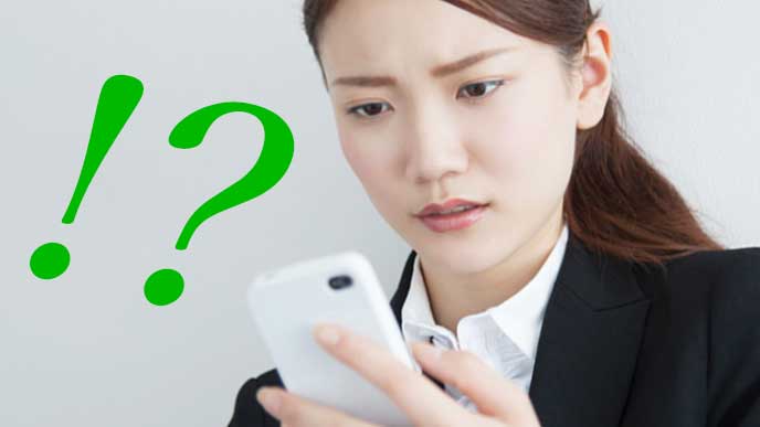 スマホを見てびっくりしている会社員の女性