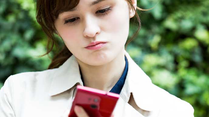 スマホを見てうんざりしている女性
