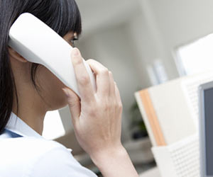 事務所で電話を受ける女性