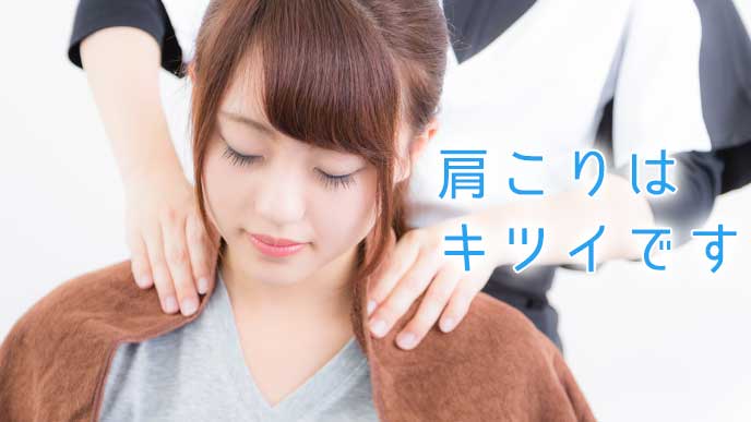 マッサージ師に肩こりをほぐしてもらっている女性