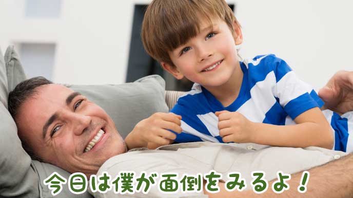 笑顔でソファに寝転がる父親と子供