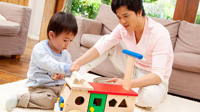 木のおもちゃで子供と一緒に遊ぶ父親