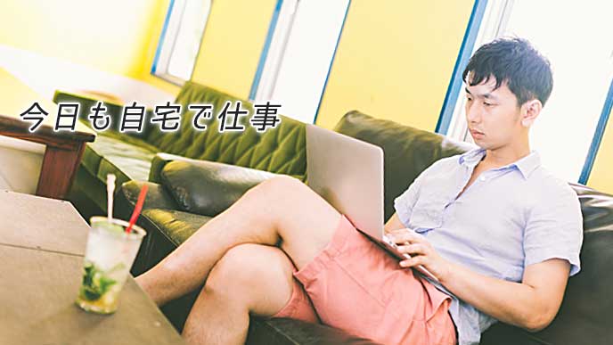 ノートパソコンを開いて自宅で仕事をしている男性