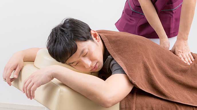 整体師からマッサージを受けている男性