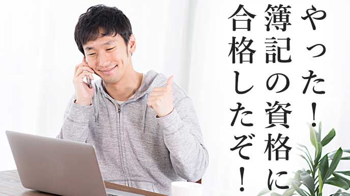 ノートパソコンを見ながら電話をして喜んでいる男性