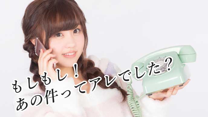 電話機とスマホを持った女性