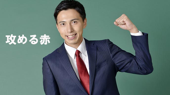 赤いネクタイを締めてガッツポーズをとるビジネスマン