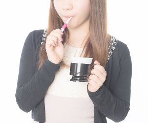 歯ブラシとカップを持つ女性