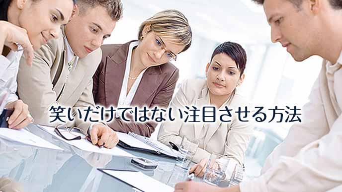 書き物をしながら手元に皆の注意をひく男性社員