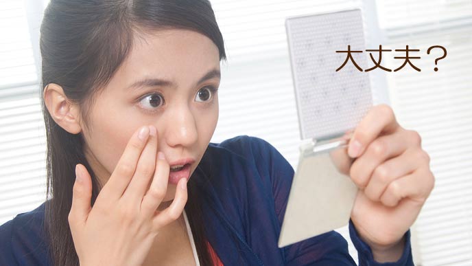 手鏡で目をチェックする女性社員