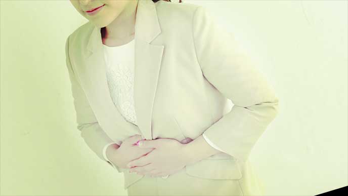 腹痛を装ってお腹を押さえるふりをしてる女性