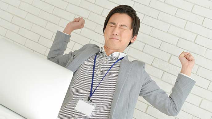 伸びをしてるスーツを着た男性