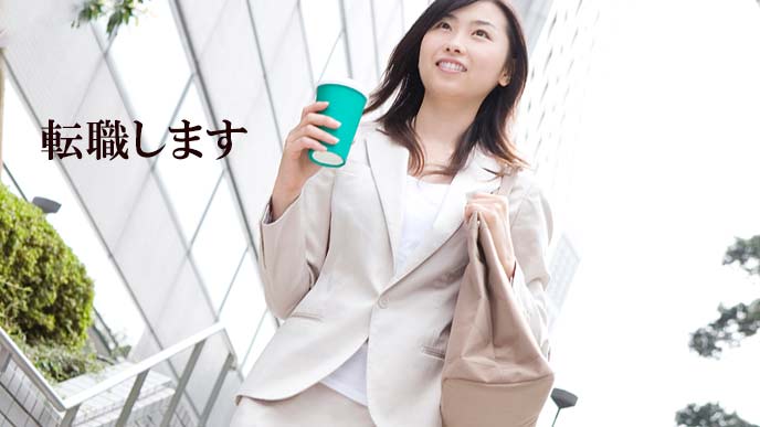 飲み物を持ってビジネス街を歩く女性