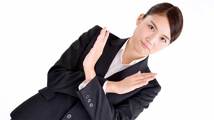バツサインを手でしてるスーツを着た女性