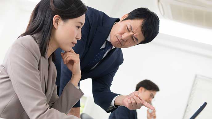 パソコン画面を指さされ上司に文句を言われてる女性社員