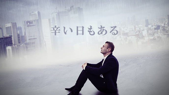 ビル街の雨天を見上げるビジネスマン