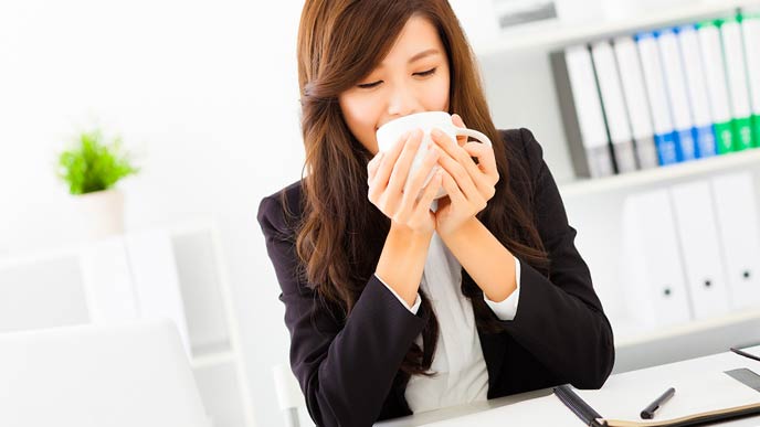 ホットコーヒーを飲む女性事務員