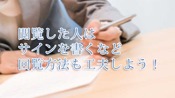 社内文書を閲覧し終わったことを記すサインをしてるスーツを着た女性