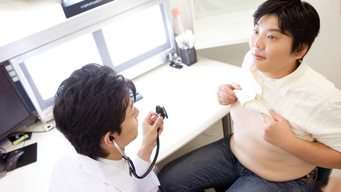 病院で診察を受けるメタボの男性