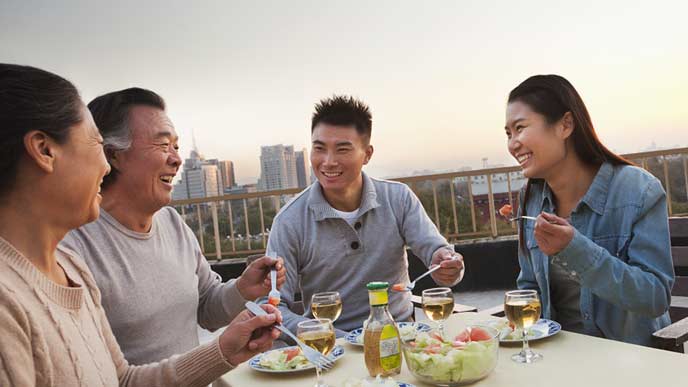 親と一緒にテラスで食事する若夫婦