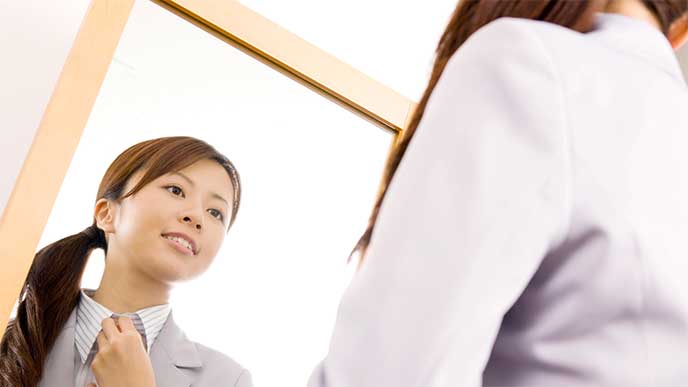 鏡を見ながら身だしなみを整えてる女性社員