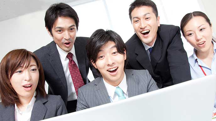みんなで一緒のパソコンを見て驚いているビジネスマンたち