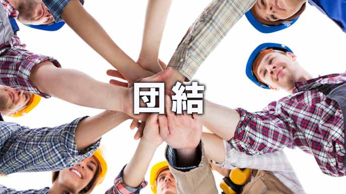 円陣を組んで手を重ねる労働者