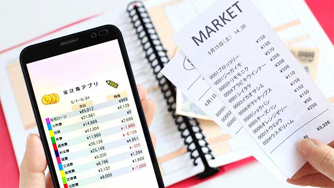 スマホのアプリで家計簿をつけてる女性