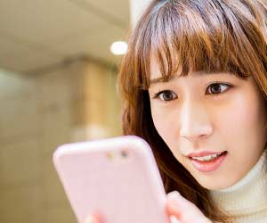スマホでメールを見て驚く女性