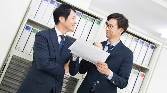 段取り工程表を確認してガッツポーズのビジネスマンたち