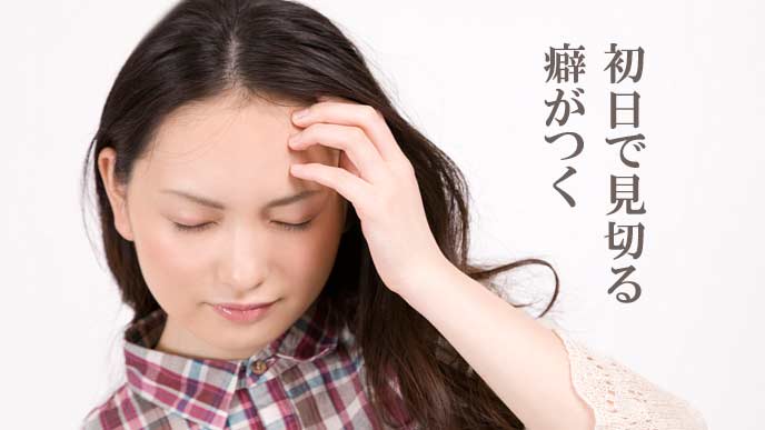 頭に手を当てながら考える女性