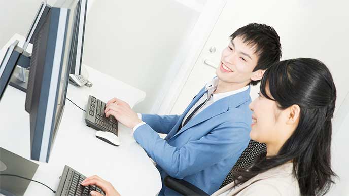 メンターと並んでパソコンを操作してる新入社員