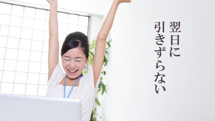 会社のデスクについて背伸びする女性
