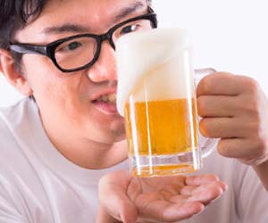 グラスの中のビールを見つめる男性