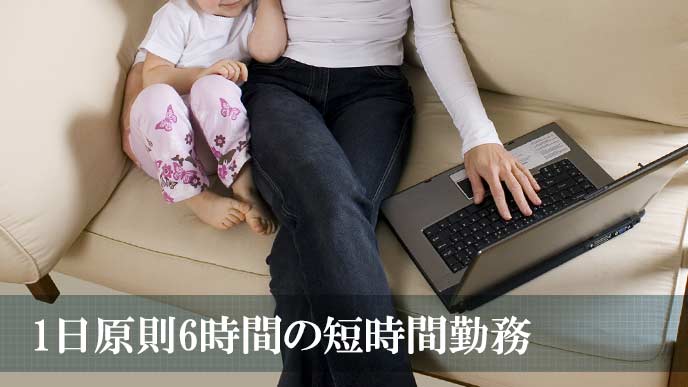 幼児を隣に座らせてパソコンを操作する母親