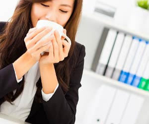 デスクでお茶を飲む女性社員