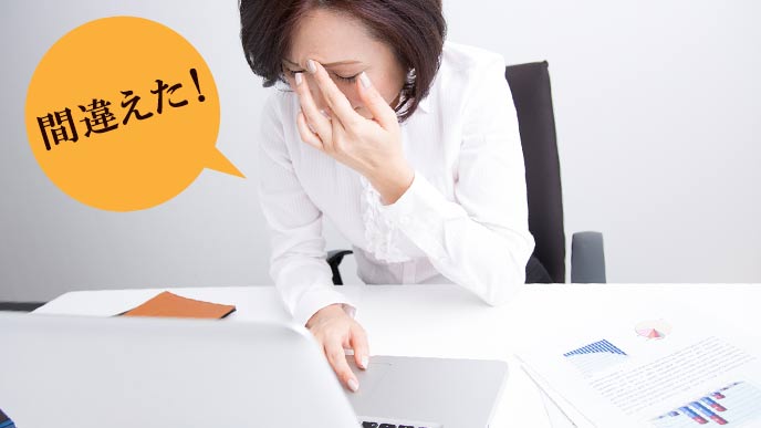 パソコンの前で自分のミスに気付く女性事務員