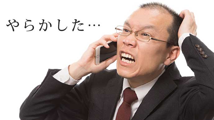 電話を片手に頭を抑えるサラリーマン