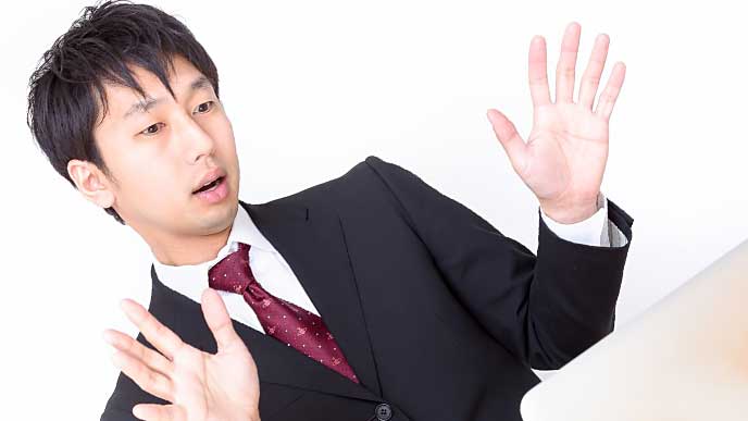 両手を広げ動揺しているサラリーマン