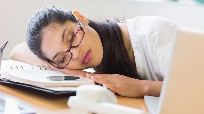 窓際で昼寝をしている会社員女性