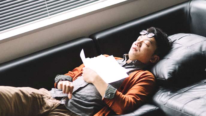 ソファーの上で眠る男性会社員