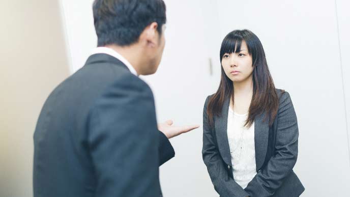 女性社員と男性上司が廊下で会話をしている