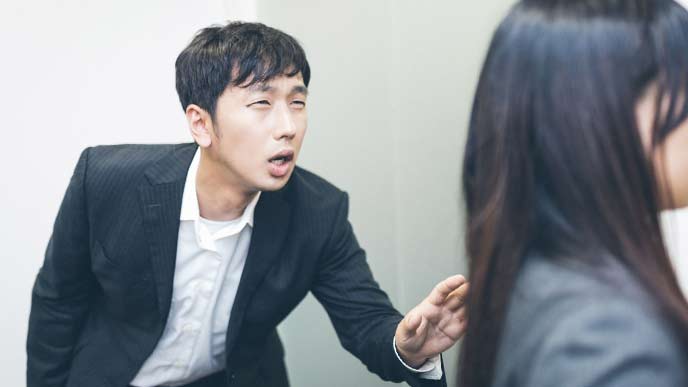 男性社員が女性社員に声をかけようとしている