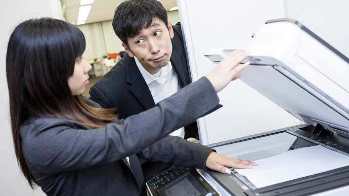 コピーをしている女性社員に話しかける男性社員
