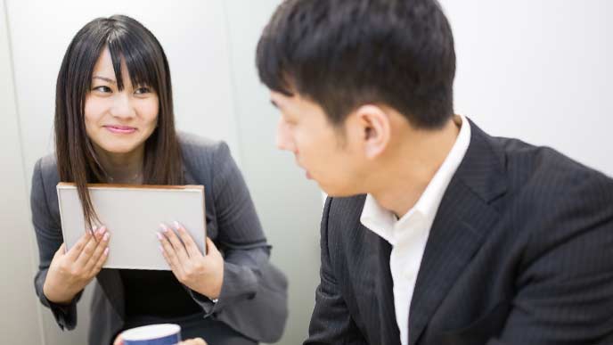 男性上司にお茶をだし、笑顔であいさつする女性