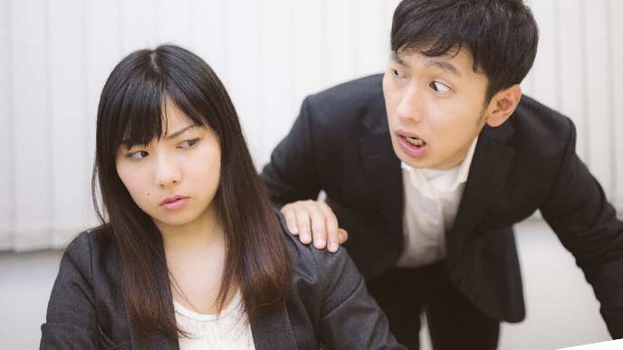 後ろから女性に話しかける男性社員