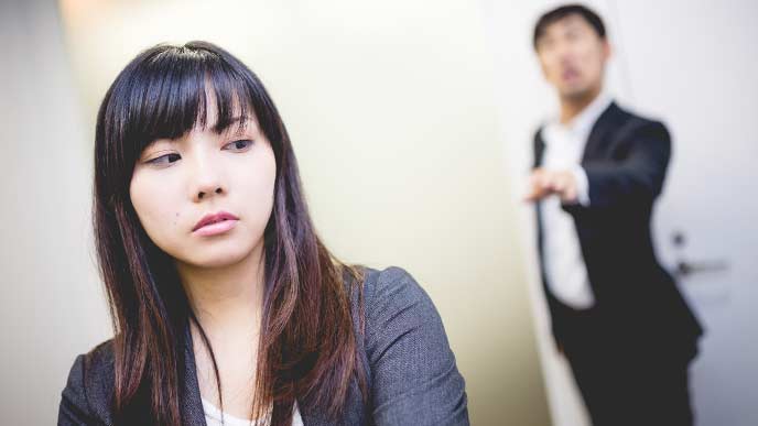 後ろから男性社員に話しかけられる女性