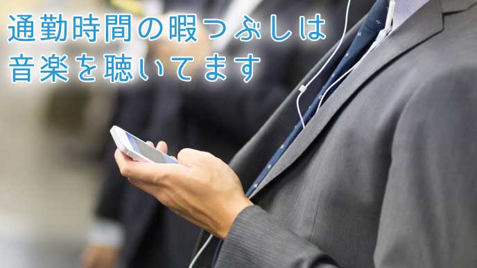 地下鉄の駅でスマホから音楽を聴いているサラリーマン
